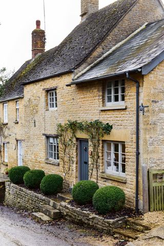 Cotswold stone cottage with box spheres