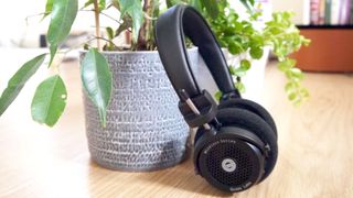 The Grado GW100s headphones leaning against a plant pot