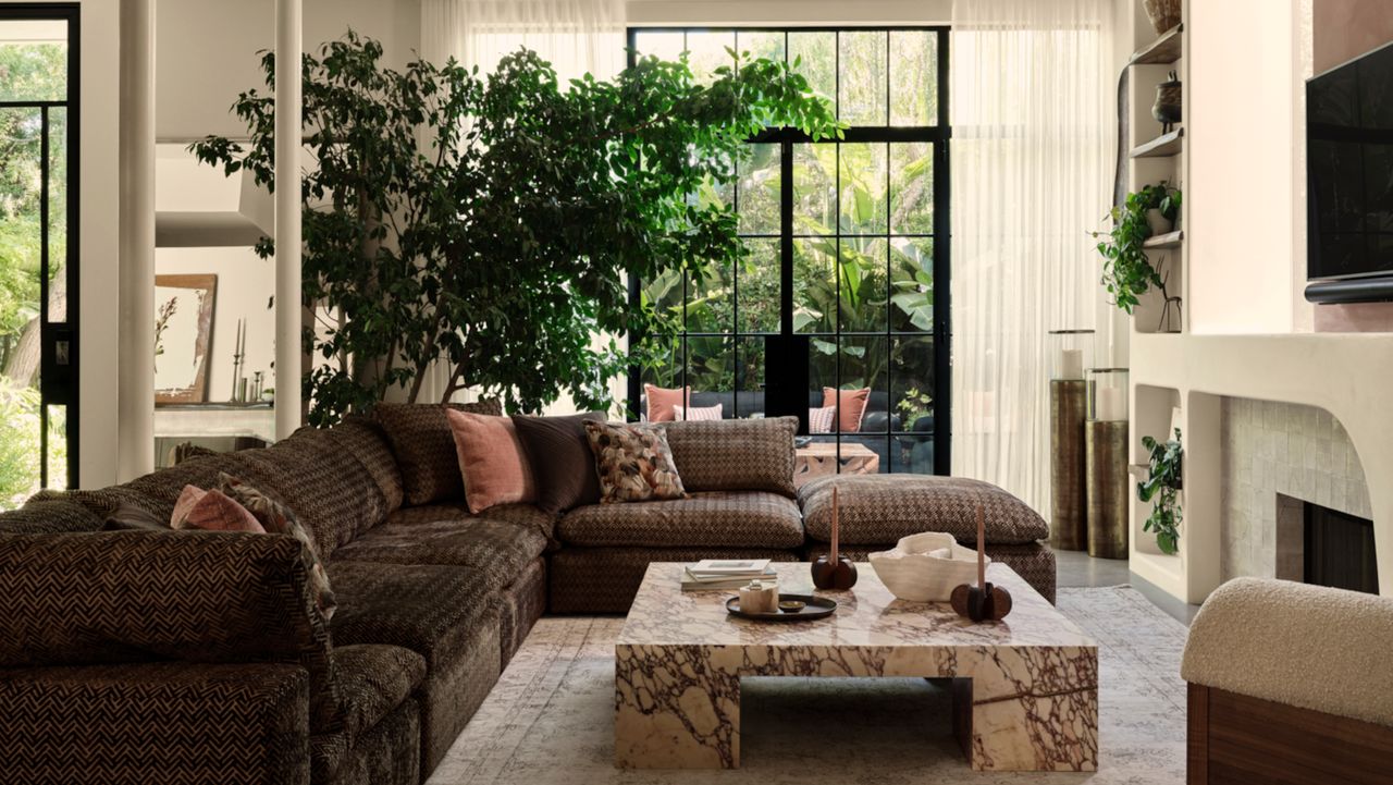 Living room with brown patterned corner sofa, marble coffee table and sculpted plaster fireplace