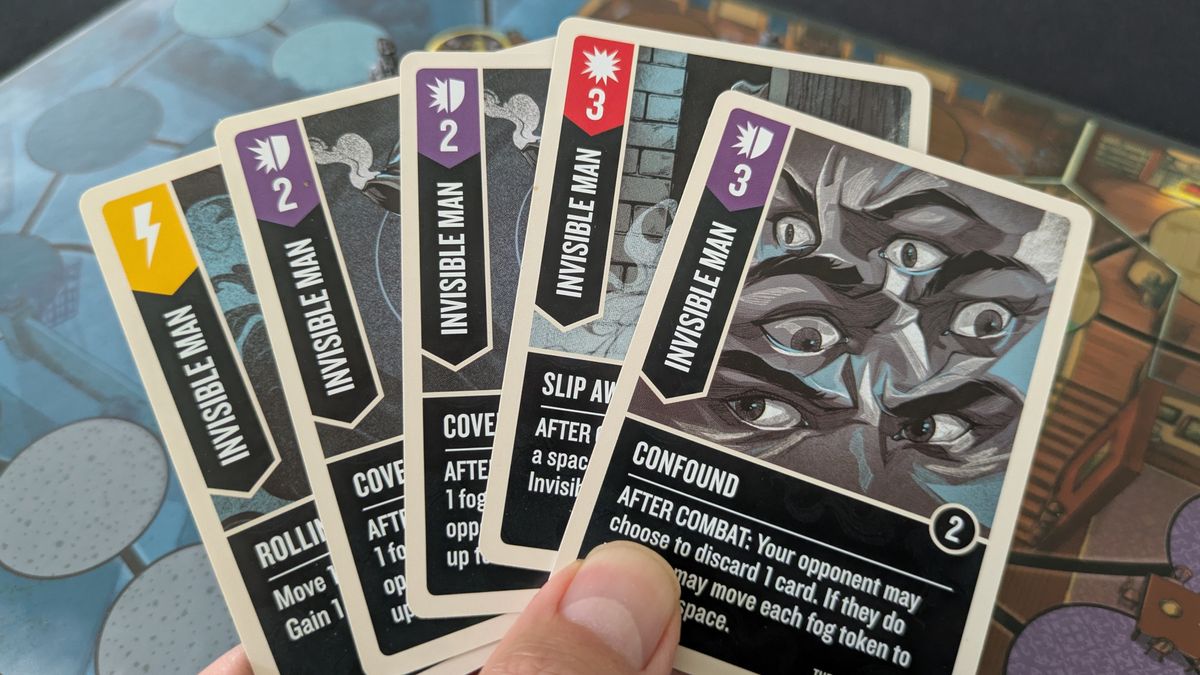 A hand holds up Unmatched: Cobble &amp; Fog cards for the Invisible Man