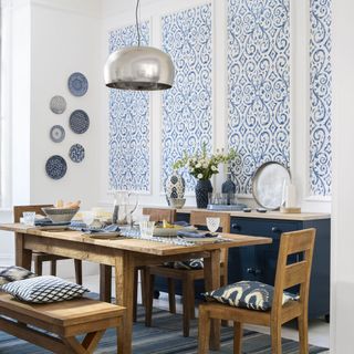 white and blue dining room with wallpapered panels and a wooden dining table