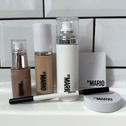 A selection of the best Makeup by Mario products stood a white surface against a white tiled background