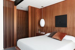 large bedroom with wood slatted wall hiding the dressing area