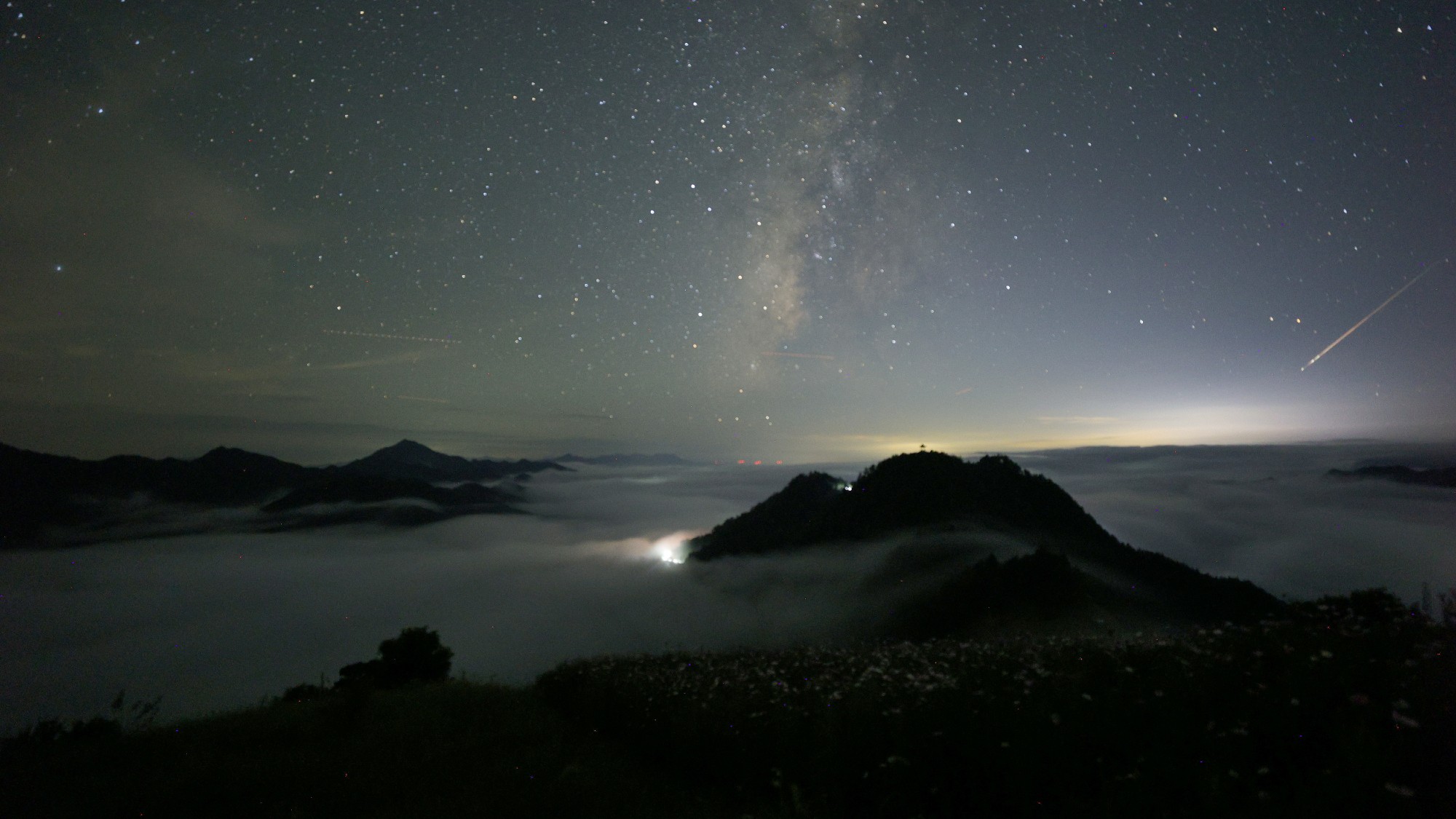 a streak of light crosses through the night sky
