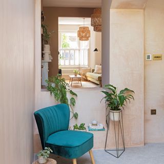 peachy tone walls with window area, and plants and teal chair