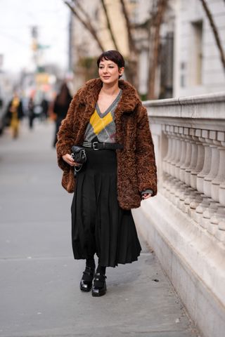A guest at new york fashion week in a fur coat and black skirt