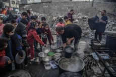 Palestinian children queue for food as volunteers distribute aid for Palestinian families displaced to Southern Gaza due to Israeli attacks, between rubble of destroyed buildings in Rafah, Gaza
