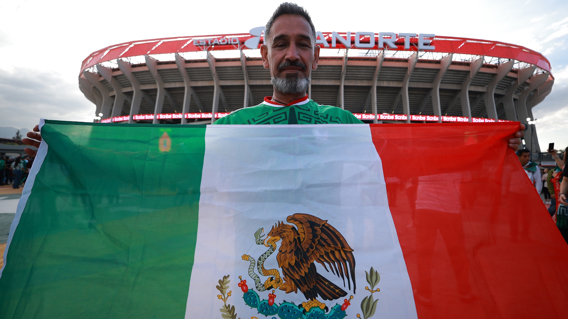 A fan shows a flag of Mexico outside the Estadio Azteca.