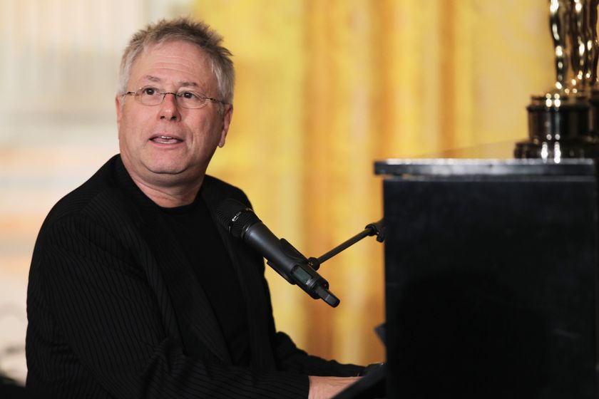 Alan Menken sitting at a piano with a microphone