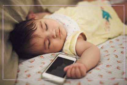 A baby sleeping next to an iPhone