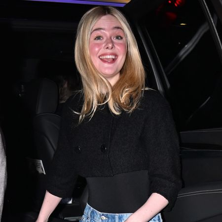 Ella fanning wears a black top with wide-leg jeans.
