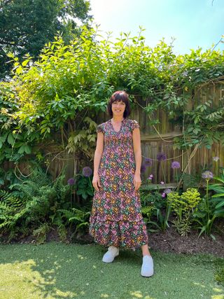 Lucy Searle wearing flower dress and white trainers stood in a garden