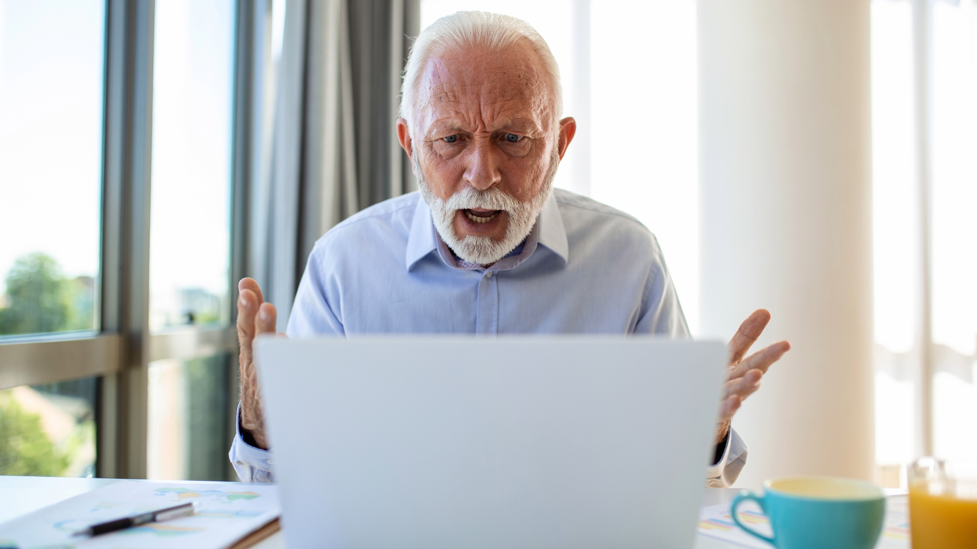 Angry stressed senior man using laptop