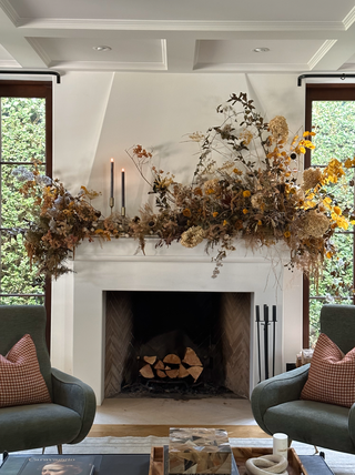 A living room with a mantel decorated with fall leaves