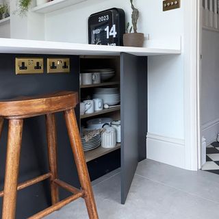 Grey kitchen breakfast bar with cupboard door open to show crockery stored on shelves
