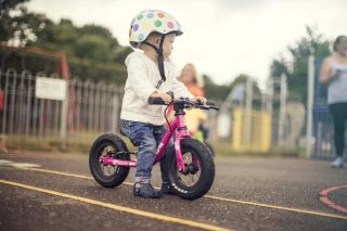 A little girl sits on a balance bike