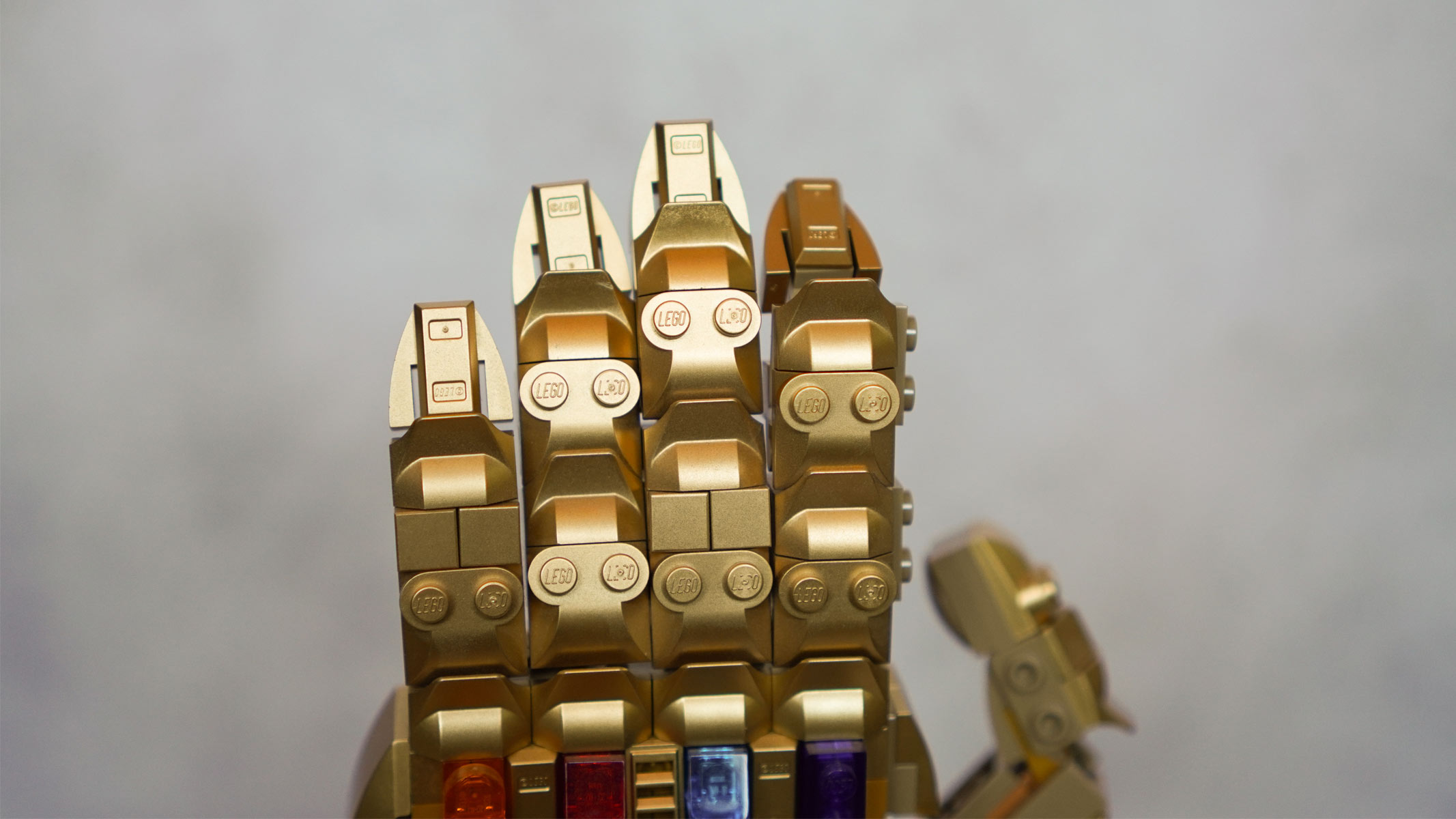 The back of a model hand made of gold bricks is placed in front of a grey background.