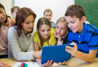 Group of kids with teacher and tablet pc at school 