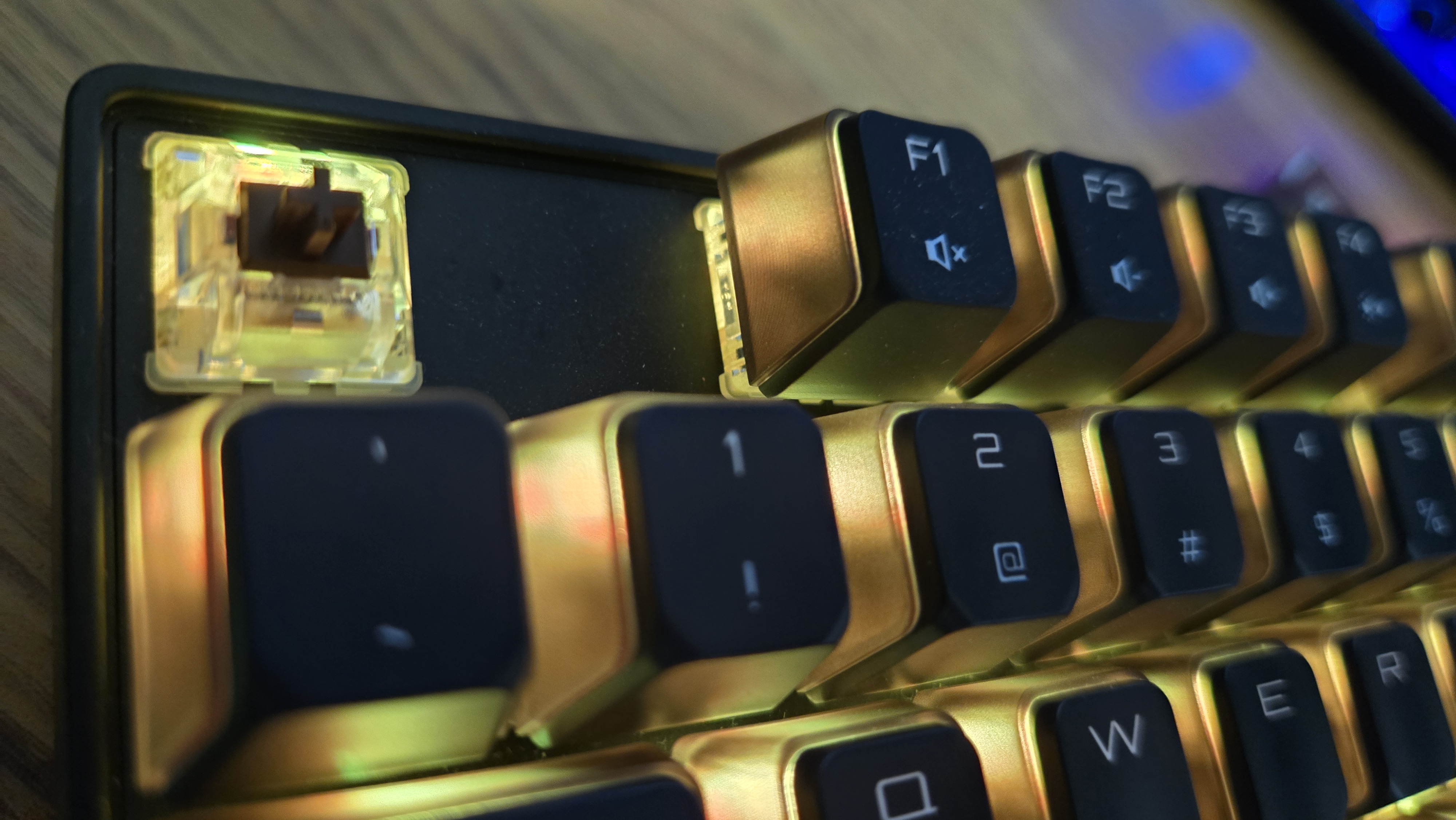 A close up of the Cherry MX 8.2 Wireless Xaga, showing one of the keycaps removed and the switch underneath. The RGB lights are on, bathing the keys in a golden light.