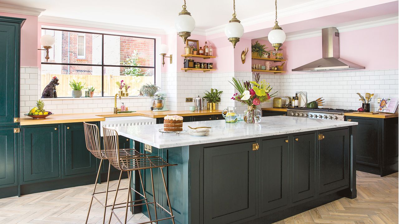 Open plan kitchen with pink walls, black Shaker style kitchen units, metro tiles splashback and rustic vintage furniture. Kitchen island with marble worktop