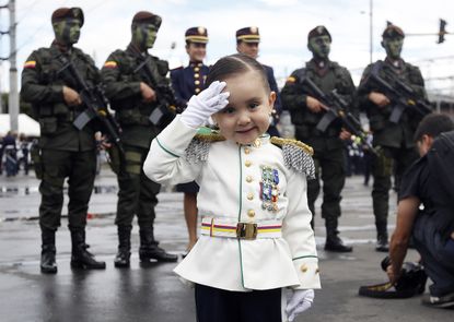 Gabriela Gomez, 3, poses for a photo decked out in a military costume before the start of a military parade.