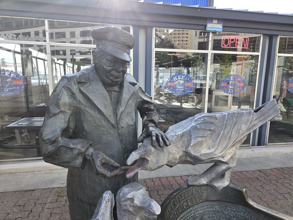 A statue of a man feeding a seagull