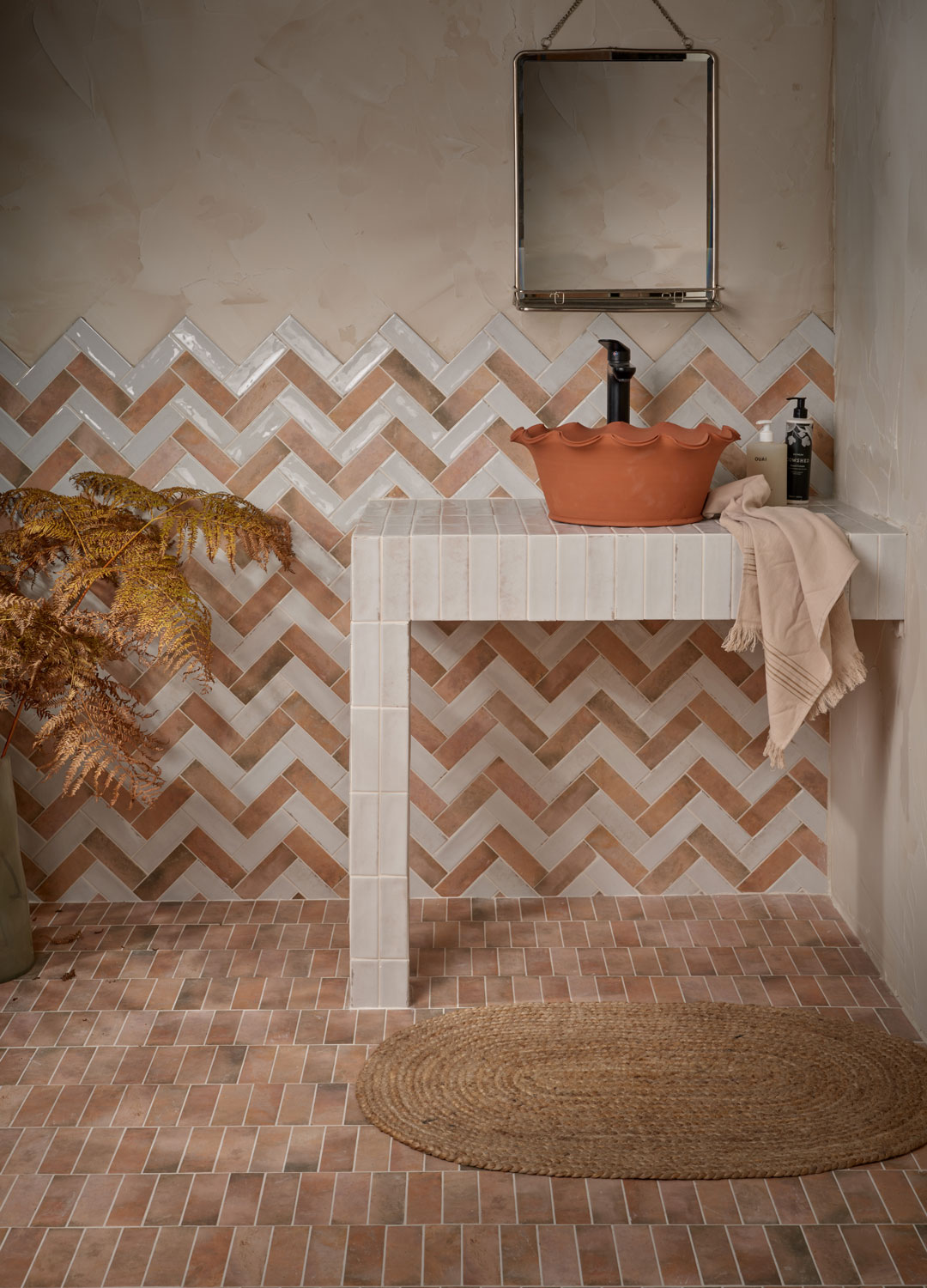 rustic bathroom with herringbone wall tiles and brick tile floor with clay hand basin