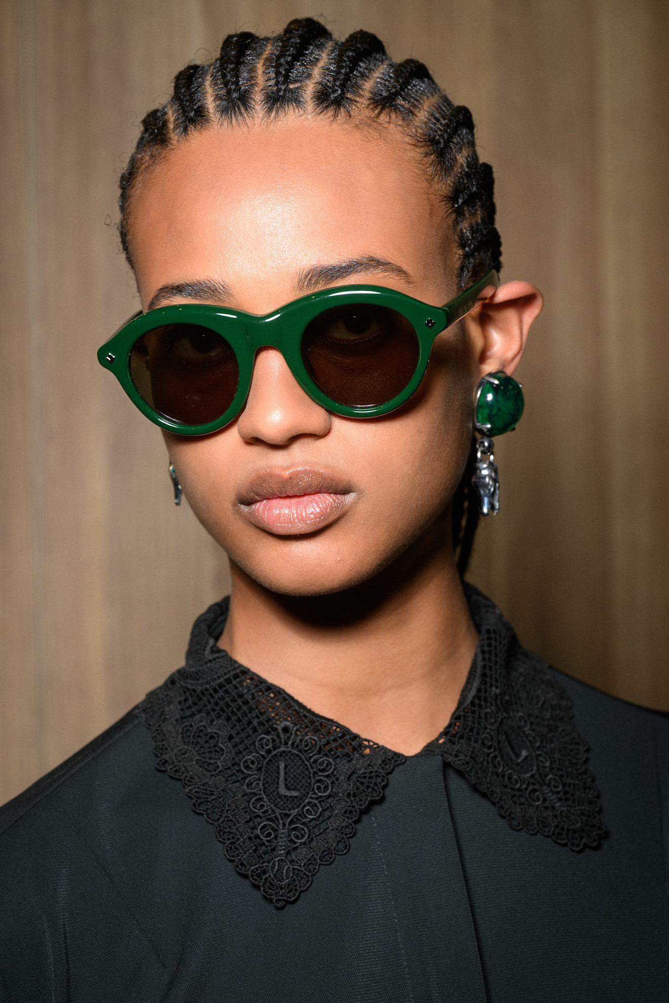 A Lacoste model wearing green gemstone earrings.