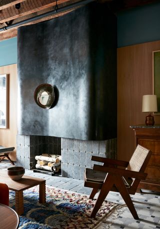 A fireplace with an oversized, curvy overmantel in smooth, black plaster finish.