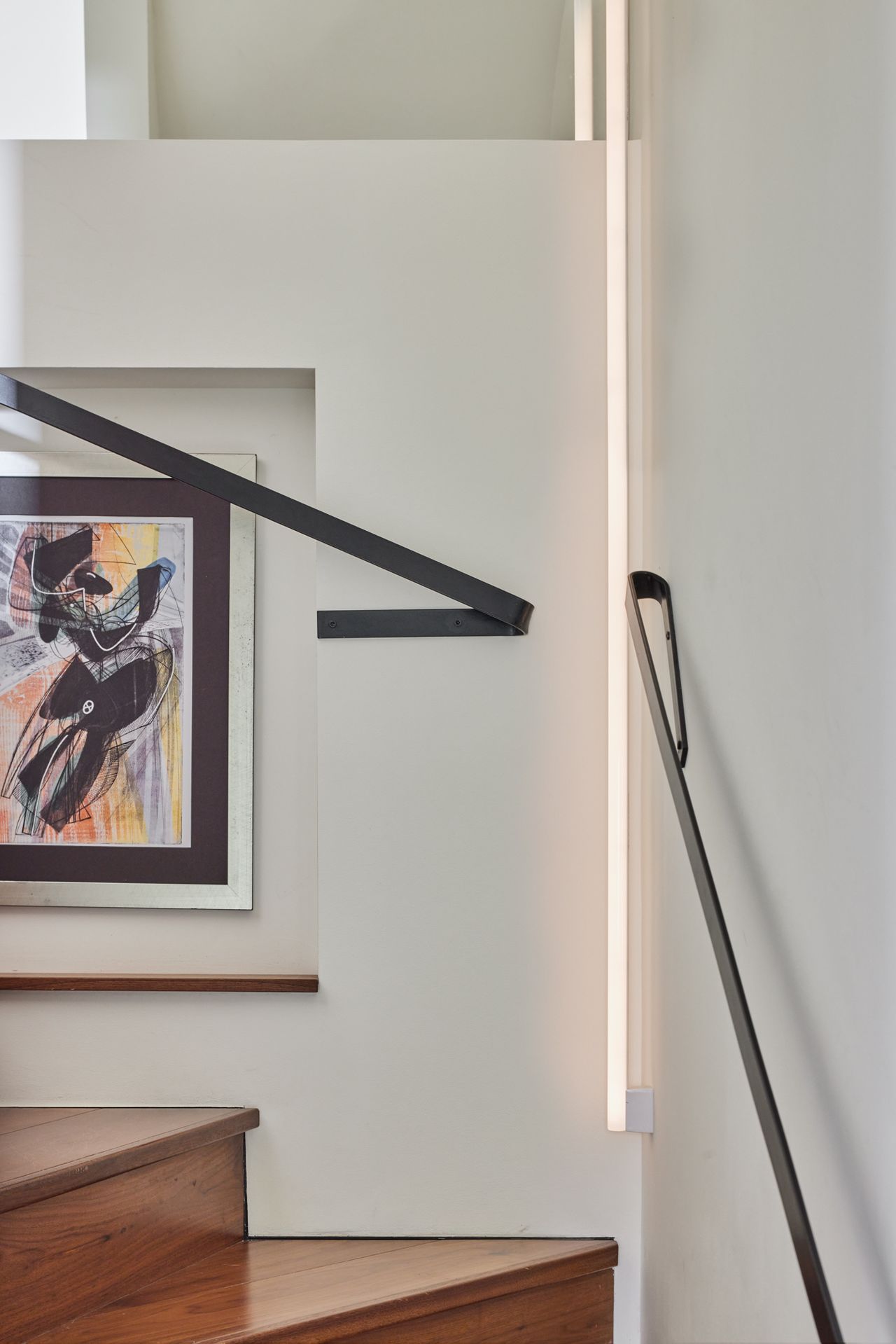 The corner of a modern staircase with an LED strip light lighting up the wall