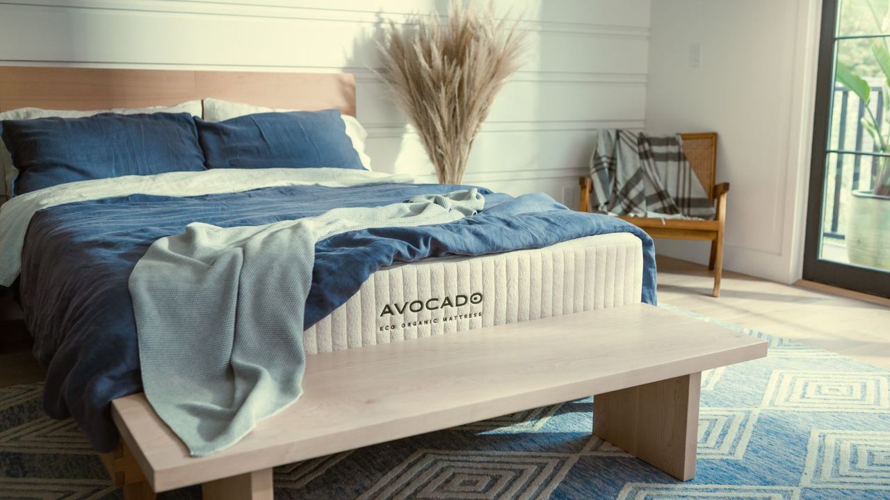 Blue and white bedding on the Avocado Eco Organic Mattress on a bed against white walls. 