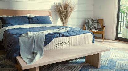 Blue and white bedding on the Avocado Eco Organic Mattress on a bed against white walls. 