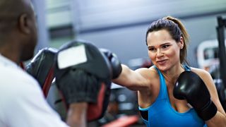 Woman boxing with her trainer: the benefits of boxing
