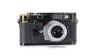 A Leica M3 black paint camera with a worn black textured finish and a chrome lens, showcasing signs of age and use