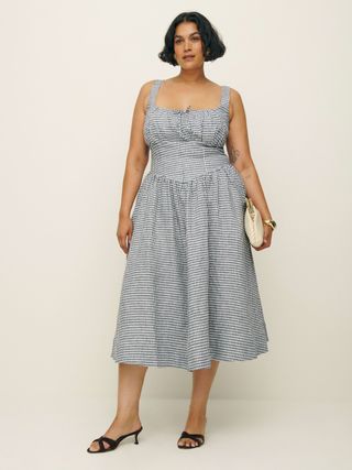 a model wears a gingham midi sleeveless dress