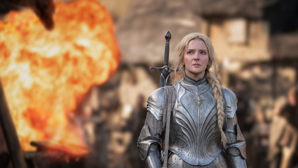 Morfydd Clark (Galadriel) is clad in armor and walks with a fire raging behind her in Lord of the Rings: The Rings of Power