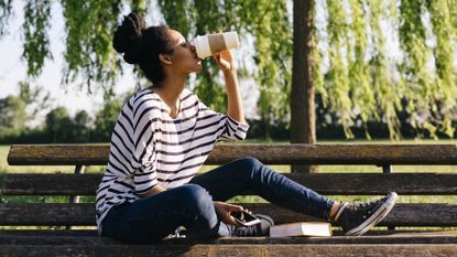 Woman drinking coffee on a park bench