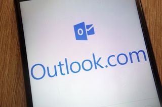 A close up of a smartphone showing a white screen with the Outlook.com logo displayed
