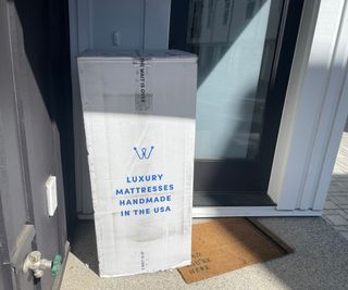 The WinkBed Luxury Hybrid Mattress in a box on a doorstep.