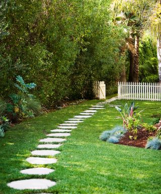 Stepping stones path leading through white picket fence