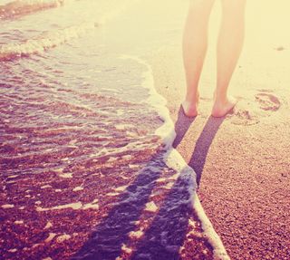 A person walks barefoot on a beach.