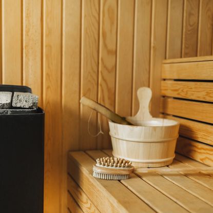 Close up of bucket and body brushes on bench in wooden sauna