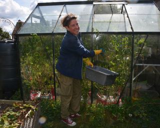 woman cleaning the exterior of a greenhouse in fall