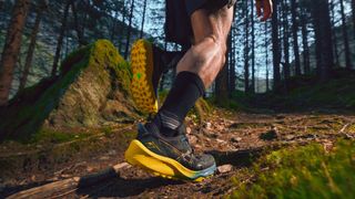 Man running off-road wearing Asics Gel-Trabuco 11 shoes