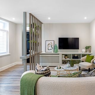 living room with wooden floor, white sofa and coffee table area, separated from entryway with a wooden partition