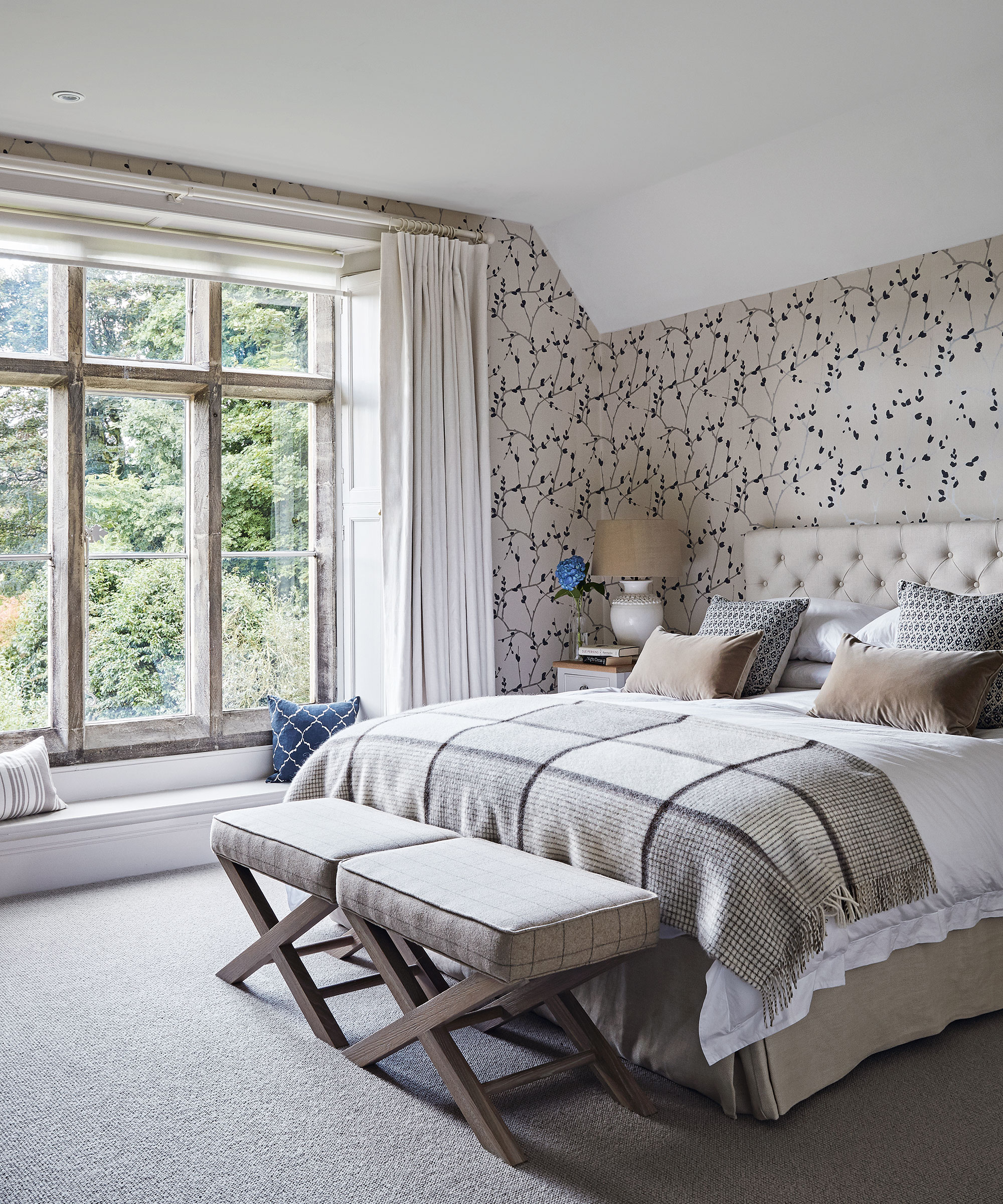 A neutral bedroom with patterned wallpaper