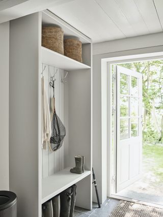 white farmhouse mud room, wooden cabinetry, gray stone flooring, door open to outside