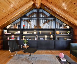 loft room with wooden sloping ceiling and black fitted furniture and steel framed Eames chair