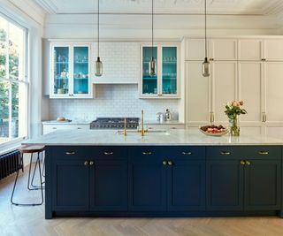 White and dark blue kitchen with glass upper kitchen cabinets over the range