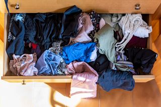 open closet drawer with messy clothes